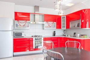 eine Küche mit roten Schränken und einem Tisch mit Stühlen in der Unterkunft Guest House v Svyatopetrovskom in Petrivs'ke
