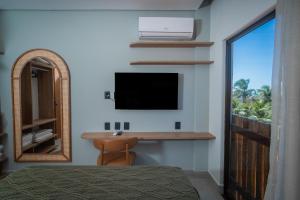 a bedroom with a flat screen tv and a desk at Be caju flats in Barra Grande