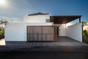 a white house with a gate and a garage at Villa Toograss close to Black Sand Beach in Keramas