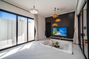 a living room with a white couch and a tv at Villa Toograss close to Black Sand Beach in Keramas