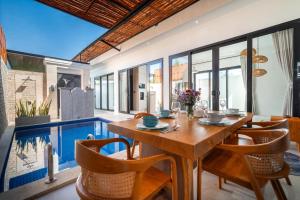 a dining room with a table and chairs and a pool at Villa Toograss close to Black Sand Beach in Keramas