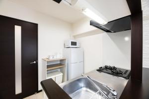 a small kitchen with a sink and a refrigerator at SPAZIO 1 Canal Hakata Annex in Sumiyoshi