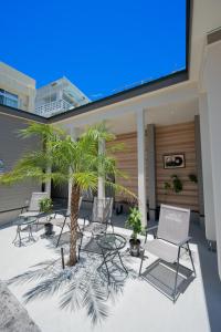 a patio with chairs and palm trees in a building at NEW OPEN! HOTEL Kozafornia in Okinawa City
