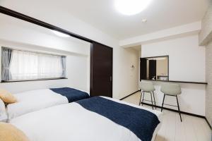 a bedroom with two beds and a table and chairs at SPAZIO 1 Canal Hakata Annex in Sumiyoshi