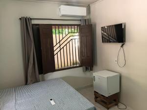 a bedroom with a bed and a window and a television at Bela Vista Pousada Alter in Alter do Chao