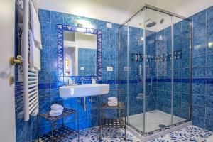a blue tiled bathroom with a sink and a shower at Starhost - CASA BETTINA enchanting seaview in Vietri sul Mare