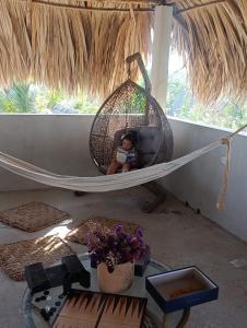 a woman sitting in a hammock in a room at Green Tree El Paredon in El Paredón Buena Vista