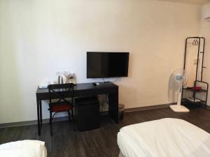 a room with a desk with a television and a bed at 信然文旅-New 凝萃海安NCH- Haian Hotel in Tainan