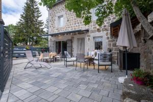 an outdoor patio with chairs and an umbrella at Gîte oya in Chaudeyrac