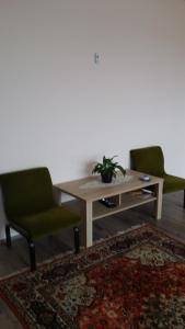 sala de estar con mesa y 2 sillas verdes en Maros Vendégház, en Mórahalom