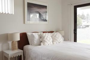 a bedroom with a bed with white sheets and a window at Beside the Seaside Gerroa Dual Family Living in Gerroa +28 photos