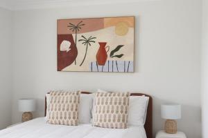 a bedroom with a bed with a painting above it at Beside the Seaside Gerroa Dual Family Living in Gerroa