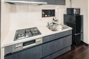 a kitchen with a sink and a black refrigerator at こだま屋 in Tokyo