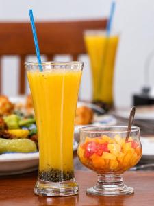 two glasses of orange juice and a bowl of fruit at Hilltop Retreat Matale in Matale
