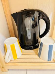 a tea kettle and two cups on a shelf at New Happy Smile-Self Check In in Tokyo
