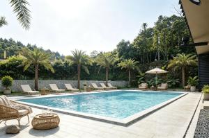 a swimming pool with chairs and trees in the background at Chyanmu Hidden Village Retreat Near The Grand Canyon of Zhangjiajie and Yellow Dragon Cave With Local Culture Village Life Breakfast Quiet Wellness Escape for Urban Travelers Seeking Privacy and Peace in Zhangjiajie