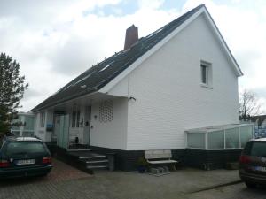 une maison blanche avec une voiture garée sur un parking dans l'établissement "Haus am Deich", à Cuxhaven