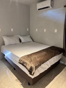 a bed with a blanket on it in a room at Pousada Bonetti Quarto 11 in Santa Rosa