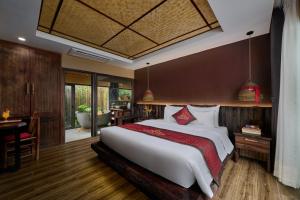 a bedroom with a large bed and a table and a desk at Tam Coc Oasis Resort & Spa in Ninh Binh