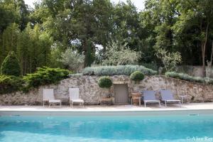阿蘭的住宿－Domaine de Mejeans - Teritoria，一组椅子,旁边是游泳池边的石墙