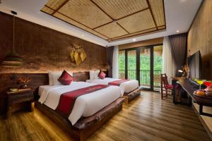 a bedroom with two beds and a desk in a room at Tam Coc Oasis Resort & Spa in Ninh Binh