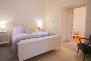 a white bedroom with a white bed and a chair at Picket Fence On Ligar in Ballarat
