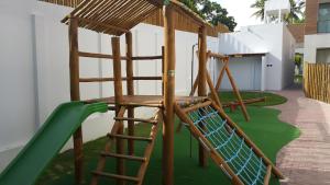 a playground with a wooden ladder and a green slide at Flat Village Imbassai in Imbassai