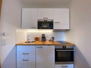 a small kitchen with white cabinets and a sink at Lachmoewe in Orth +16 photos