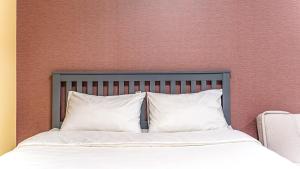 a bed with white pillows in front of a wall at Geoje Memory Kidspoolvilla in Geoje