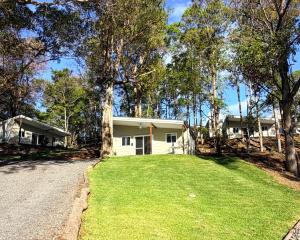 a house with a grassy yard next to a road at Sunshine Coast Hinterland Retreat - Yandina Station in Yandina Creek