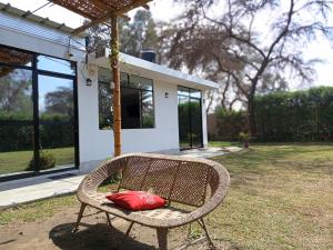 a red pillow sitting on a wicker chair in a yard at Casa Rústica Diaz in Ica