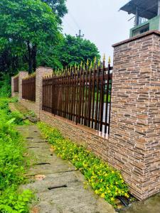 a brick fence with a gate and yellow flowers at The Siiying in Pāsighāt +12 photos