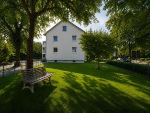 a bench sitting in the grass in front of a white house at Ferienwohnung Gartenblick in Laupheim