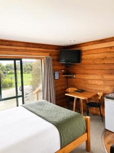 a bedroom with a bed and a desk and a television at Shining Star Beachfront Accommodation in Hokitika