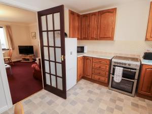 a kitchen with wooden cabinets and a white refrigerator at Harbour Side in Maryport