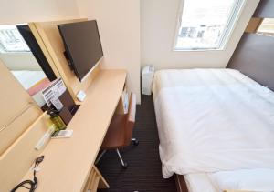 a room with a bed and a desk with a television at Super Hotel JR Nara Ekimae Sanjo Dori in Nara