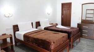 a bedroom with two beds and a dresser and a mirror at Adam's Palm Resort in Talaimannar