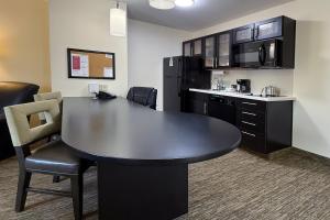 an office with a table and a kitchen with appliances at Candlewood Suites East Lansing by IHG in Lansing