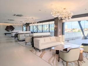 a living room with couches and tables and windows at oneTree Plaza Hotel Cebu in Cebu City