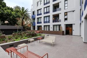 a courtyard with benches and tables in front of a building at THREE43 ON B - Fluent Serviced Apartments in Cape Town