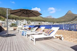 a row of lounge chairs on a deck with an umbrella at THREE43 ON B - Fluent Serviced Apartments in Cape Town