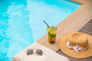 a straw hat and a drink next to a swimming pool at Koon Hotel Sukhumvit in Bangna