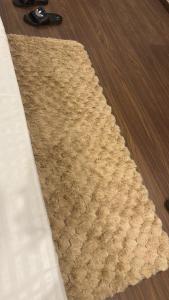 a tan rug on a wooden floor with a remote at Luxura stays in Greater Noida +1 photo