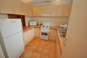 a kitchen with a white refrigerator and a sink at Seaview on Kent in Rockingham +2 photos