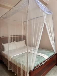 a bedroom with a canopy bed with white curtains at Zone hotel and guest house in Bugembe