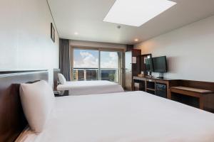 a hotel room with two beds and a television at 씨뷰 호텔 in Naedo-dong