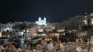 a group of people sitting at tables at night at Eugene Sea Side Suite in Naousa