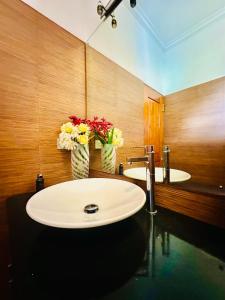 a bathroom with two sinks and two vases with flowers at Shek Residence in Colombo