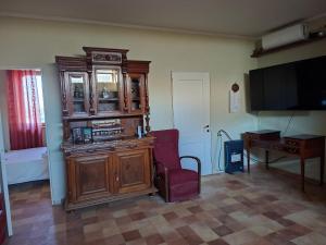 a living room with a large wooden cabinet and a chair at Villa Radiosa in Gravina in Puglia