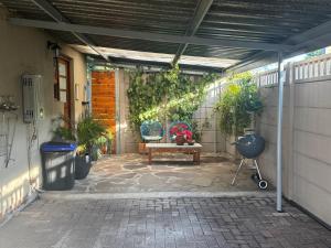 a patio with a bench and potted plants at Open Room Comfort in Cape Town